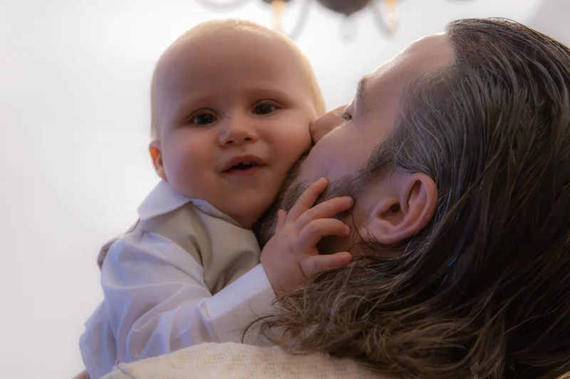 Un adulte embrasse la joue d’un bébé souriant.